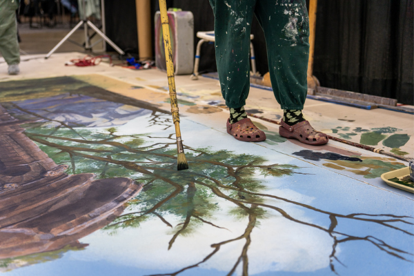 a person painting a set with a long paint brush at the paint lab