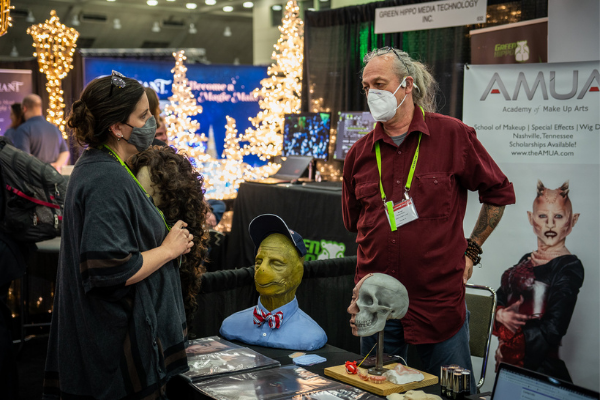 a person talking to another person at a booth on the expo floor