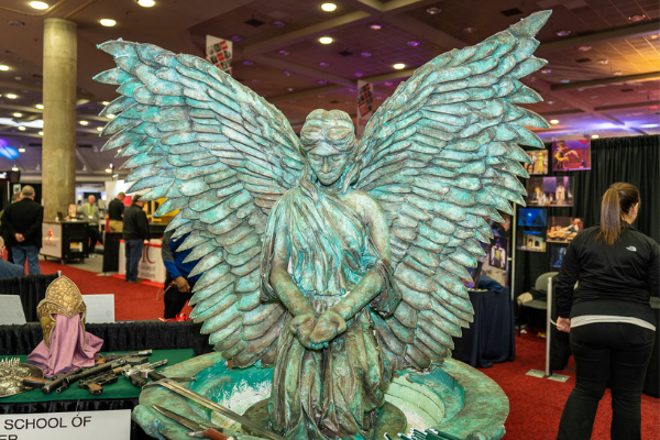 a green angel statue on the expo floor