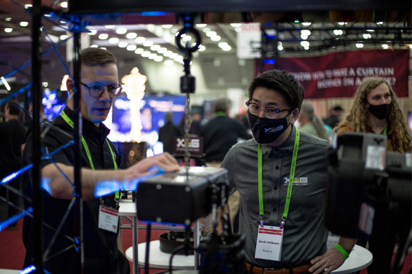 Two individuals testing lighting at a booth on the Expo floor