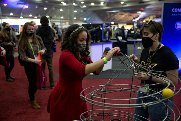 An individual playing with a wire model toy on the Expo floor