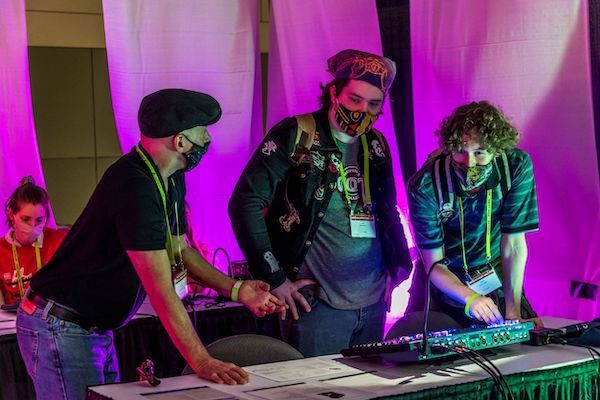 a group of three people getting hands on with a light board on the expo floor