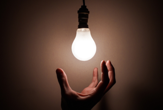 Open hand underneath hanging lightbulb